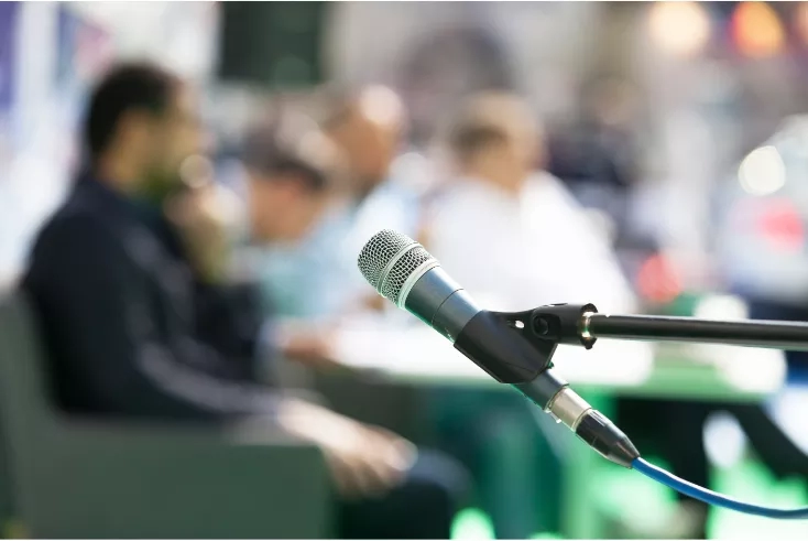 Close up of a microphone with a blurred group of people in the background.