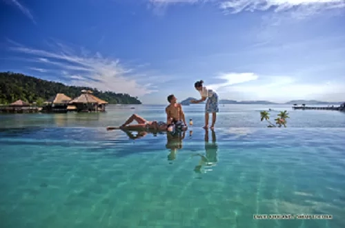 A couple is relaxing at the island pool at Shangri-La's Rasa Ria Resort.