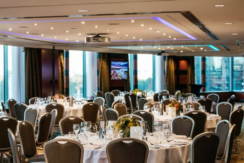 Cambridge Room with tables set for dinner and a view of the city through the windows.