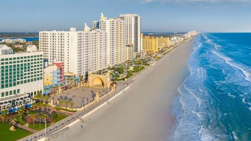 A view of a beach with a resort and buildings on the shore in Daytona Beach.