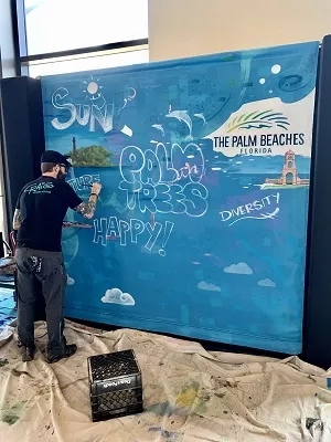 Man painting on a large canvas at Palm Beach Convention Center, Florida.