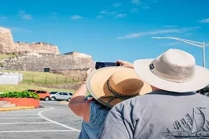 Tourists in hats take pictures of Fort San Felipe del Morro in Puerto Rico.