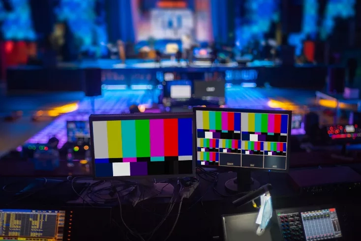 Two monitors are showing colorful bars in a studio with a stage in the background.