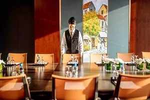 A butler standing at the end of a conference table in a meeting room at JW Marriott Hanoi.