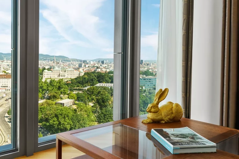 Glass table with a rabbit figurine and a book titled "Very Vienna" in a room of Andaz Vienna.