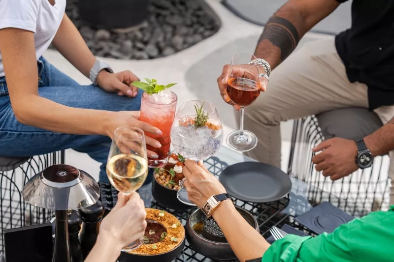 Four people are enjoying food and drinks in a rooftop garden in Barcelona.