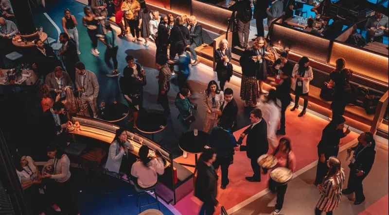 A busy event venue with many people, colorful decor, and a lively atmosphere.