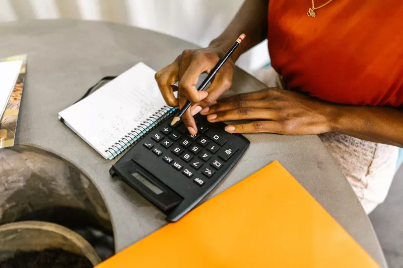 A woman calculating her budget with a calculator and a notebook.