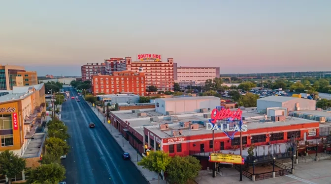 Aerial view of Billy Bob's Dallas with cars on the road and trees on a sunny day.