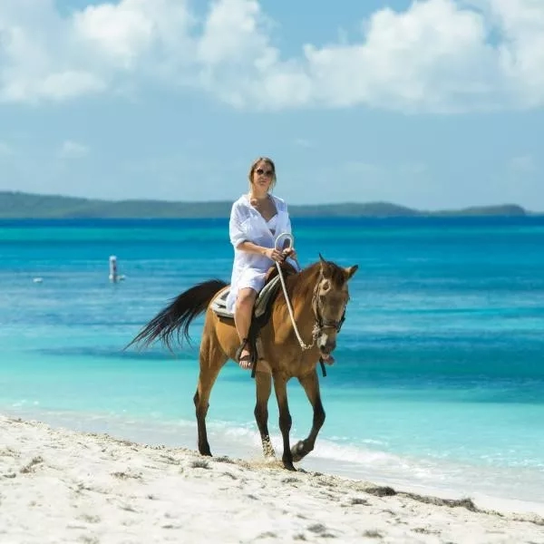 A woman is riding a horse on the beach while enjoying her stay in Puerto Rico.
