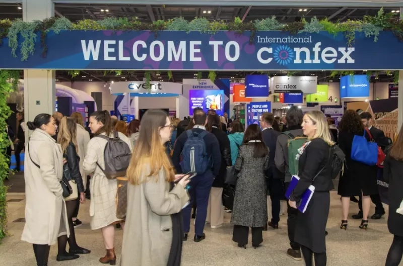 A group of people are standing in front of the Welcome to International Confex banner.