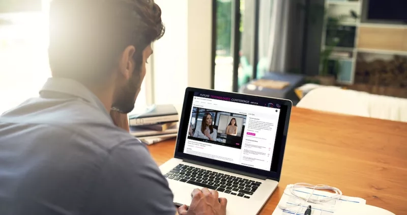 Man watching a video call on his laptop at the office, showing the Future Technologies Conference.