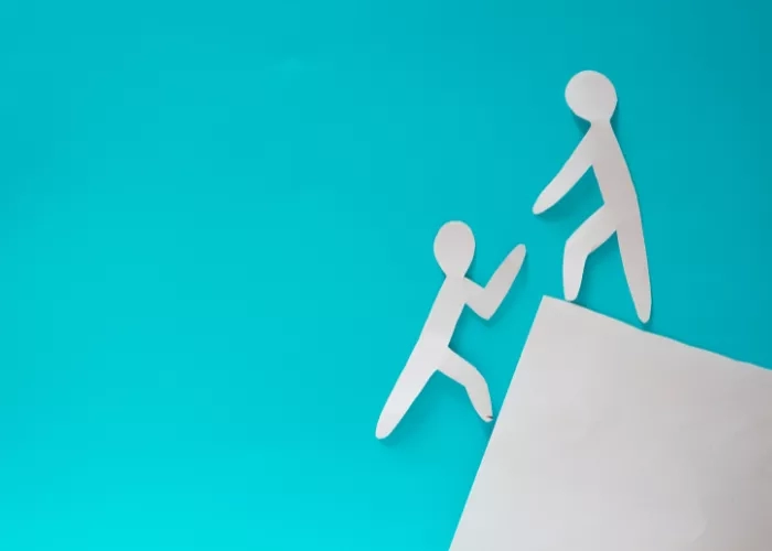 Two paper people climbing up a mountain on a blue background.