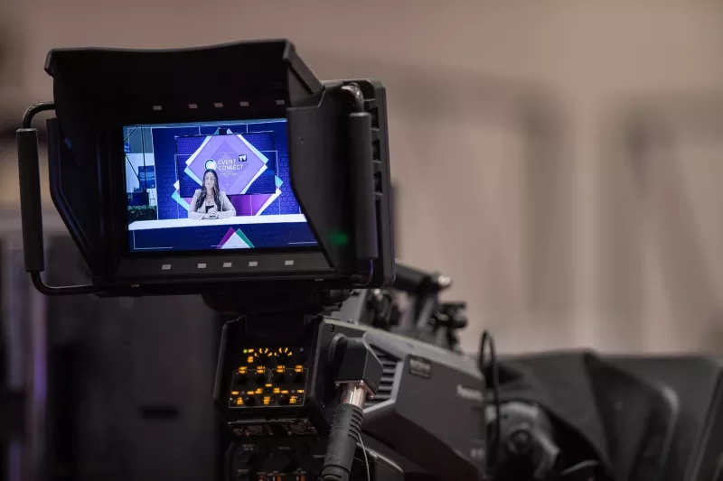 A camera filming a woman who is reporting for an event.
