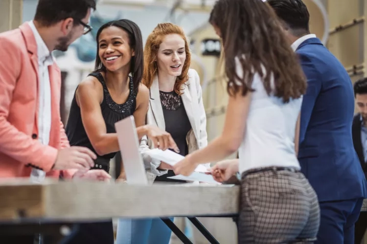 Group of people discussing and signing documents at the table with the help of a business analyst.