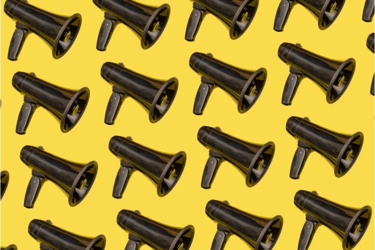 Black megaphones on a yellow background to represent the voice of the customer in marketing.