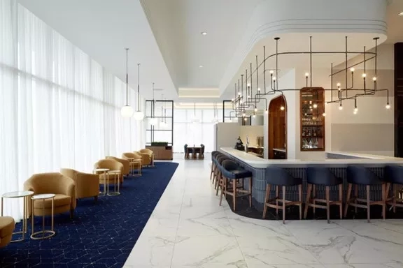 The lounge of The Ritz-Carlton, Sarasota with chairs, tables, and a bar counter.