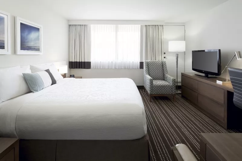 A bedroom with a king bed, a chair, and a TV at EVEN Hotel Rockville.