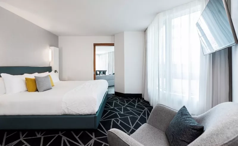 A king guest room with a gray armchair at Le Méridien New Orleans.