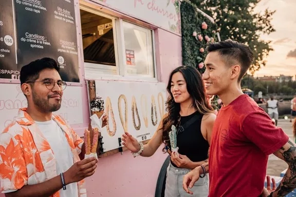 Three friends standing in front of Jane Churro food truck in Montreal during summer.