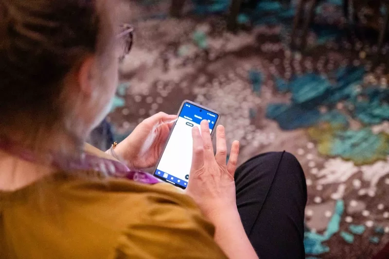 Woman using event app on her phone at a conference in the Grand America Hotel.