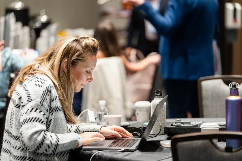 A project manager works on a laptop at a table during Cvent CONNECT 2023.