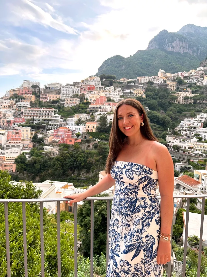 A woman in a blue dress standing on the balcony of a villa in Positano.