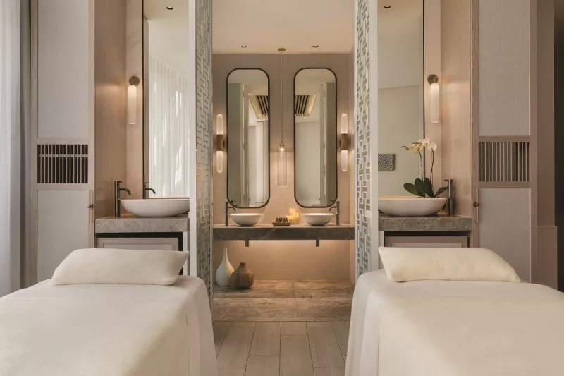 A serene spa treatment room with two beds, dual sinks, and soft lighting at Chuan Spa.