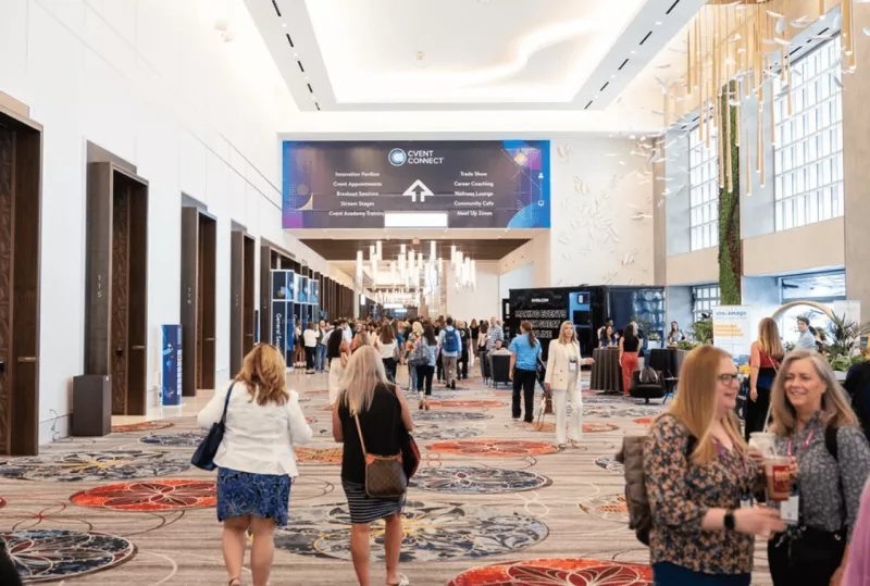 A group of women are walking through a hallway with a banner hanging from the ceiling.