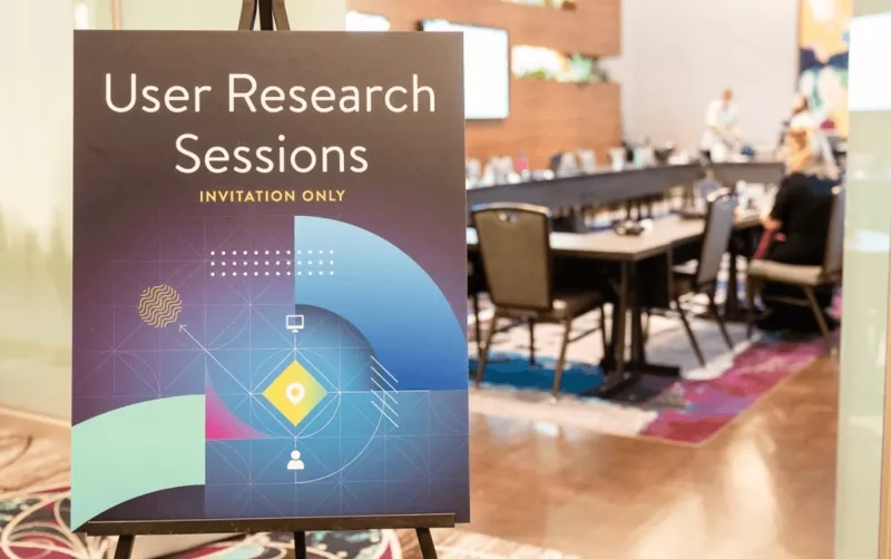 A poster that reads User Research Sessions stands in front of a conference room at the AHA Annual Meeting.