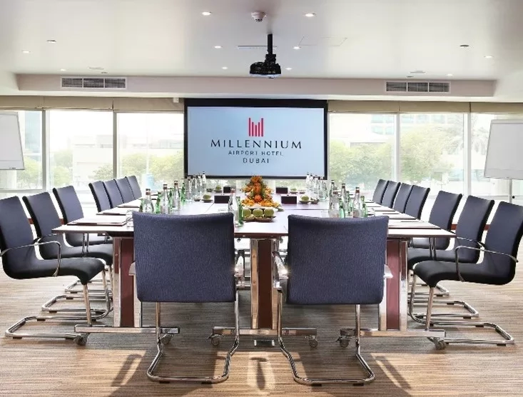Meeting room with a long table and chairs at Millennium Airport Hotel Dubai.