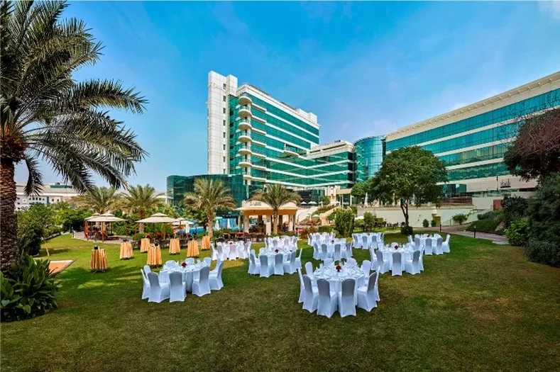 Outdoor lawn with dining setup at Ramee Guestline Hotel in Dubai, featuring architecture and landscaping.