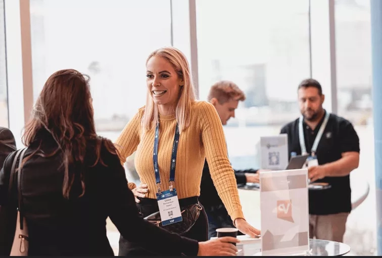 Networking event with blonde woman talking to another woman in front of a counter.