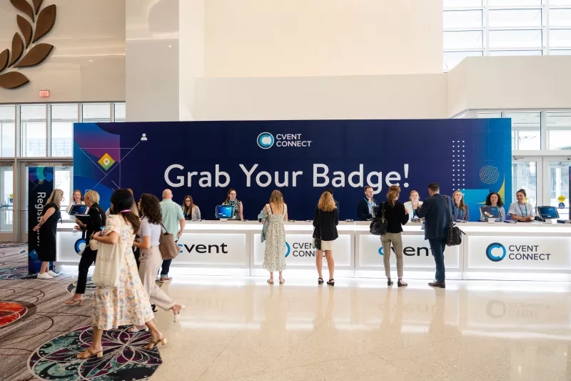 Cvent Connect 2023: Event registration counter with people in the background and a large Cvent Connect banner.