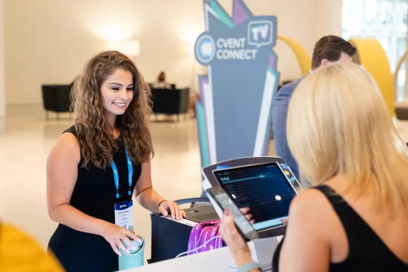 Two women interacting with each other at the Cvent CONNECT booth with the Cvent Connect logo.