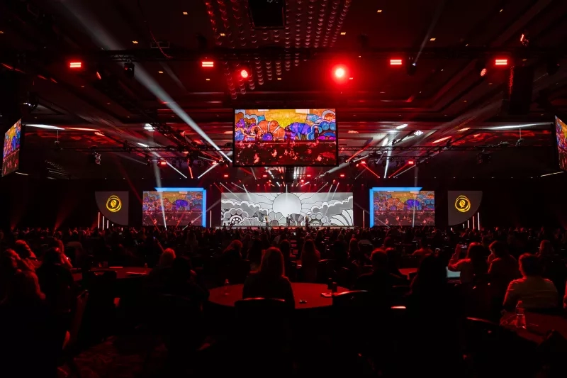 Crowded room with red lights and a stage with a large screen during Cvent CONNECT 2023.