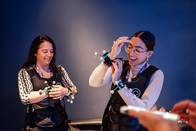 Two women wearing vests holding molecular models smile at an event at the Museum of Science.