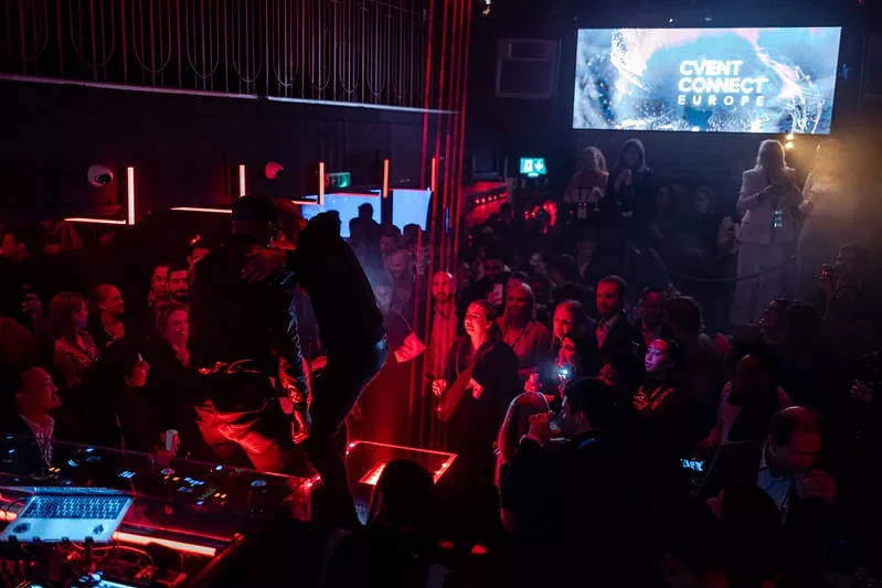 A night event with two people on a stage with a large screen displaying the text "CVENT CONNECT EUROPE."