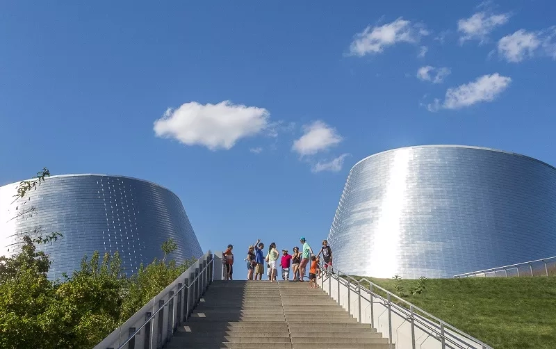 Tourists on the stairs in front of the Montreal Museum of Fine Arts with a blue sky.