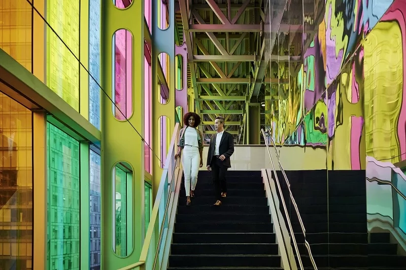 A couple walking up the stairs with a colorful wall in the background at Hotel Bonaventure Montreal.