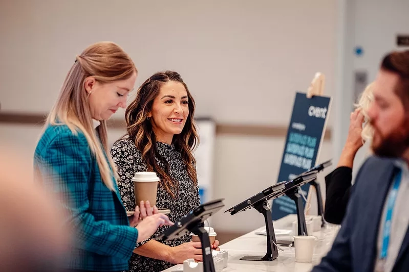 Two people standing at a check-in desk serving customers 