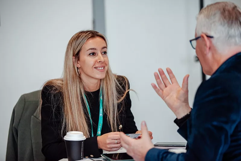 A man and a woman sitting across from eachother discussing their portfolio