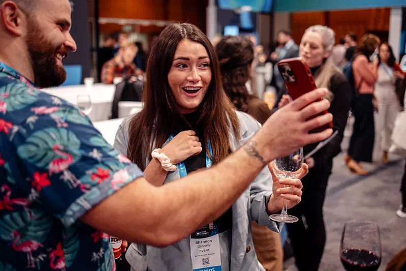 A man and a woman at happy hour laughing and viewing images on their phones