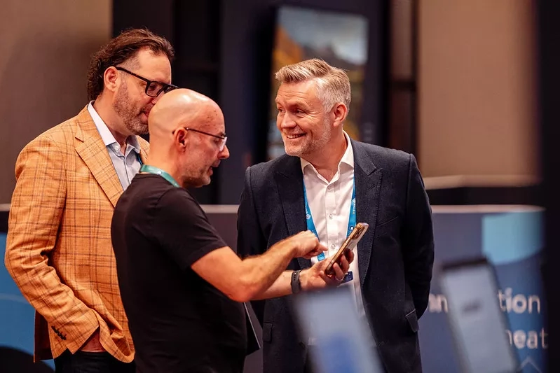 Two people reviewing AI tools on another person's cell phone at an event 