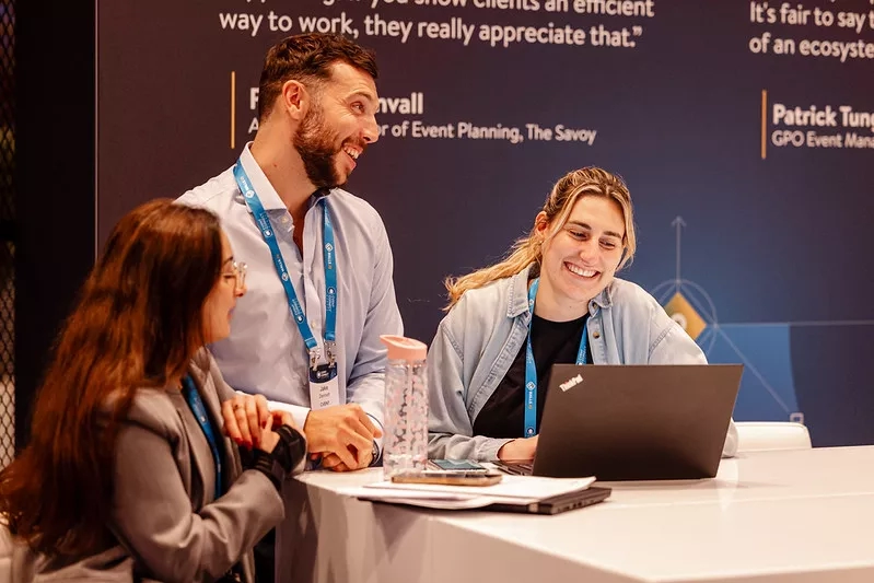Three people sitting around a desk discussing AI customer service tools at an event