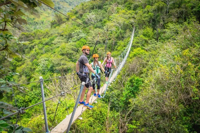 Three people walking on a hanging bridge in the forest at Toro Verde Adventure Park.