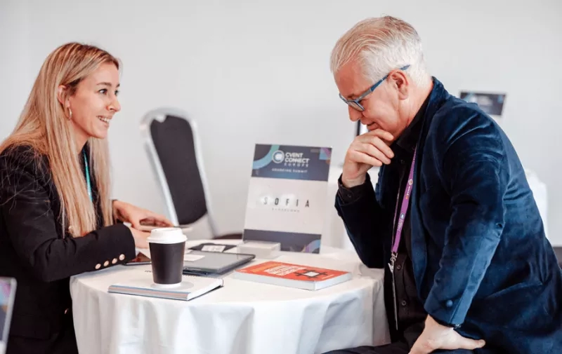An old man and a young woman sit at a table and have a meeting.