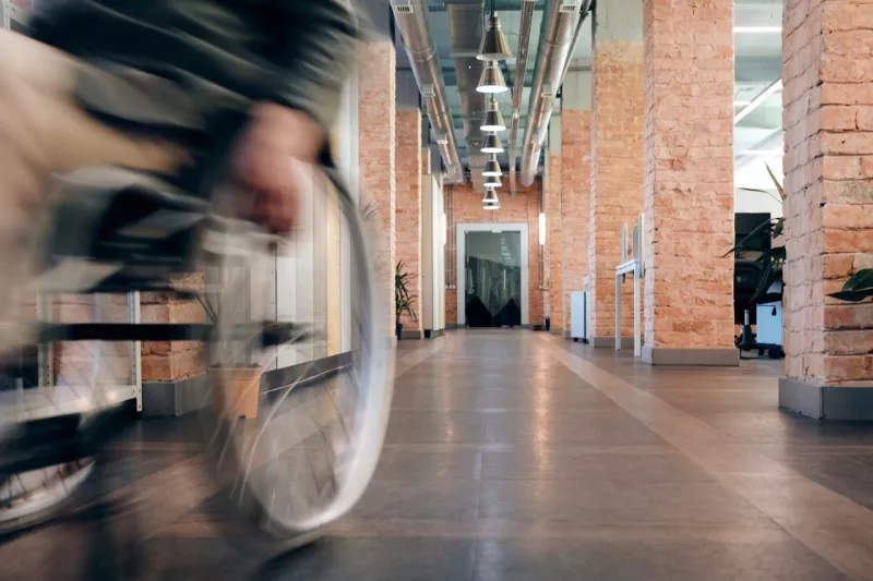Blurry photo of a person in a wheelchair inside a hallway of a brick building.