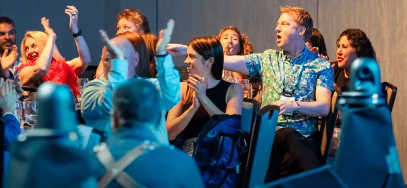A group of people are sitting in chairs and raising their hands in the air.