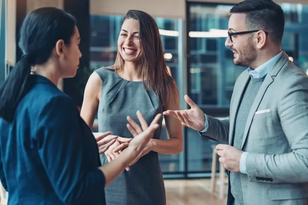 Three business people having a meeting in the office with a smile on their faces.